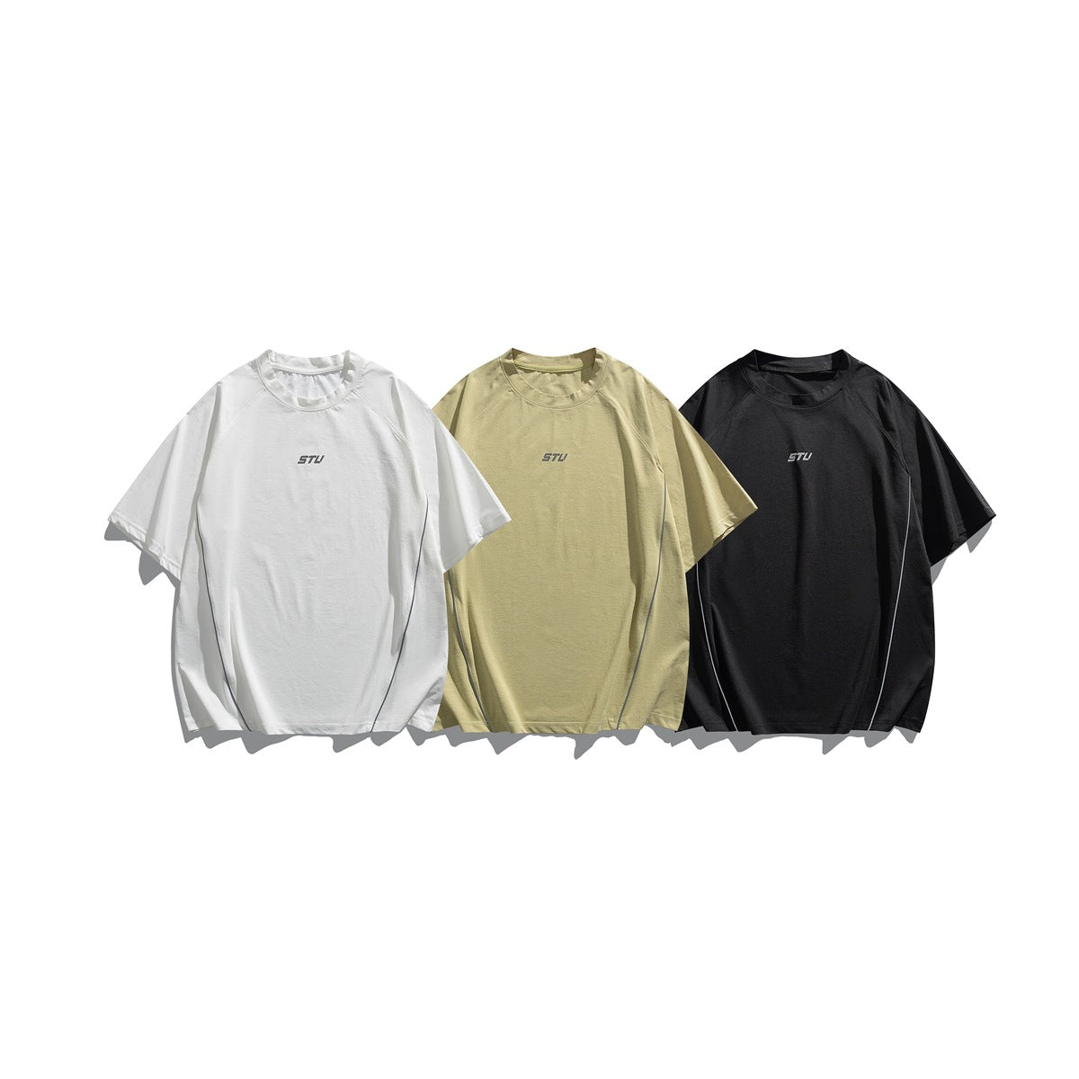 Three loose-fit short-sleeve crew-neck T-shirts in white, pale olive, and black, each with a small chest logo.