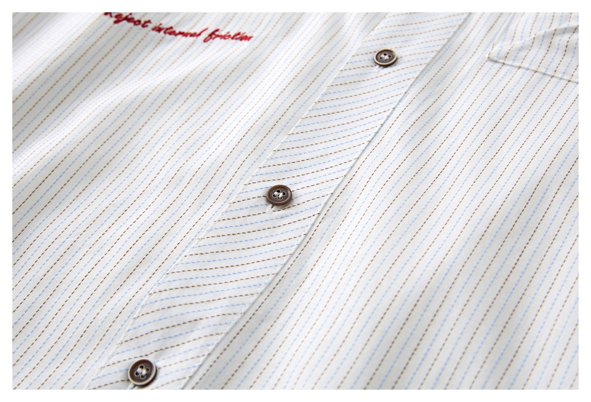 Close-up of the white shirt’s blue and brown striped button placket with dark buttons.