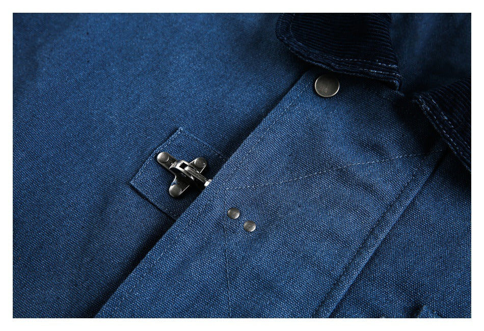 Close-up of a blue jacket showing a metal clasp, rivets, stitching, and collar edge.