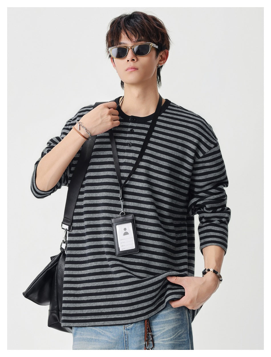 Model wearing a black and gray striped long-sleeve henley with a short button placket.