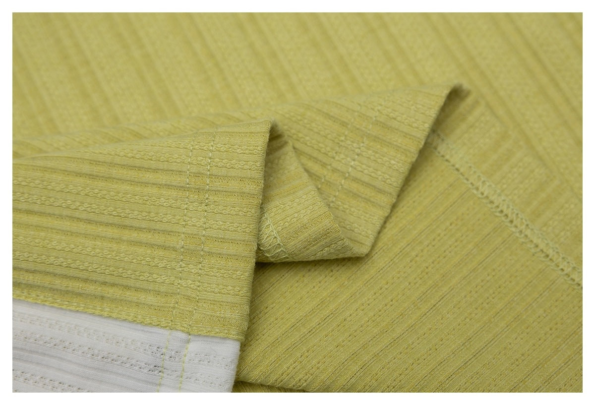 Close-up of the pale yellow shirt's stitched hem and textured fabric.