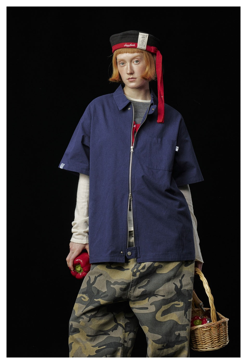 Front view of a model wearing an oversized navy short-sleeve zip shirt with a collar and chest pocket.