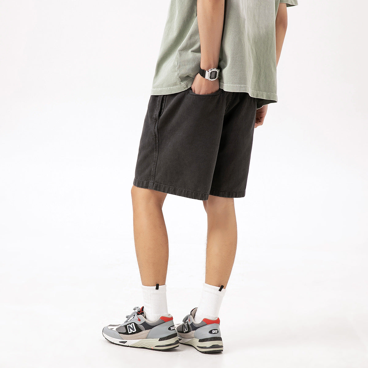 Rear three-quarter view of a model wearing charcoal drawstring shorts with a loose fit.