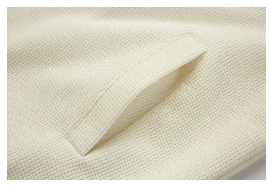 Close-up of a slanted welt pocket on cream textured fabric.