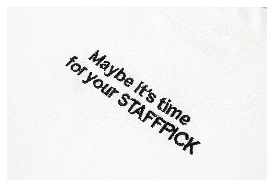 Close-up of black embroidered text reading “Maybe it’s time for your STAFFPICK” on a white T-shirt.