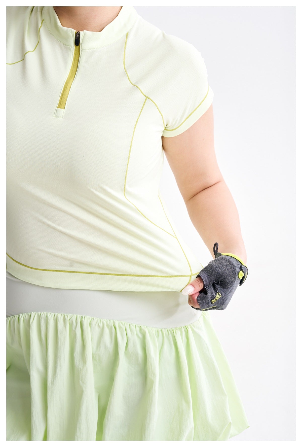 Close-up of a pale yellow-green zip-neck top with curved contrast seams and a matching bubble skirt waistband.