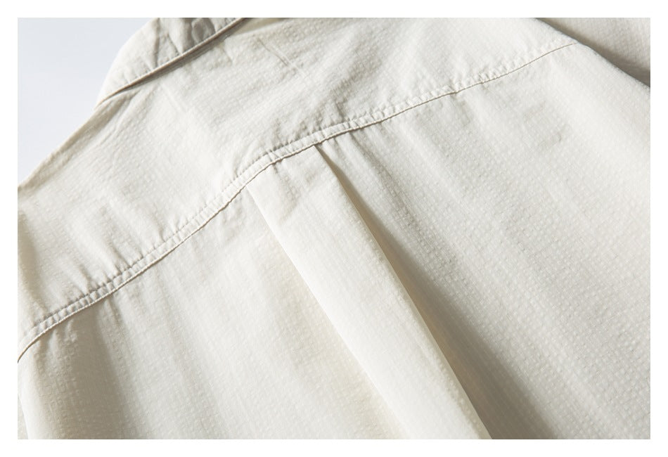 Close-up of an ivory shirt's back yoke seam and central pleat.