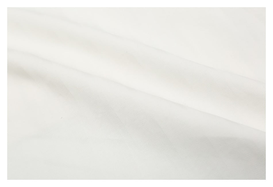 Close-up of off-white fabric draped in broad folds, showing a fine diagonal texture.