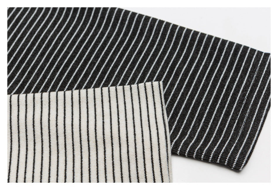 Close-up of black-and-white striped garment fabric showing two contrasting stripe directions and finished edges.