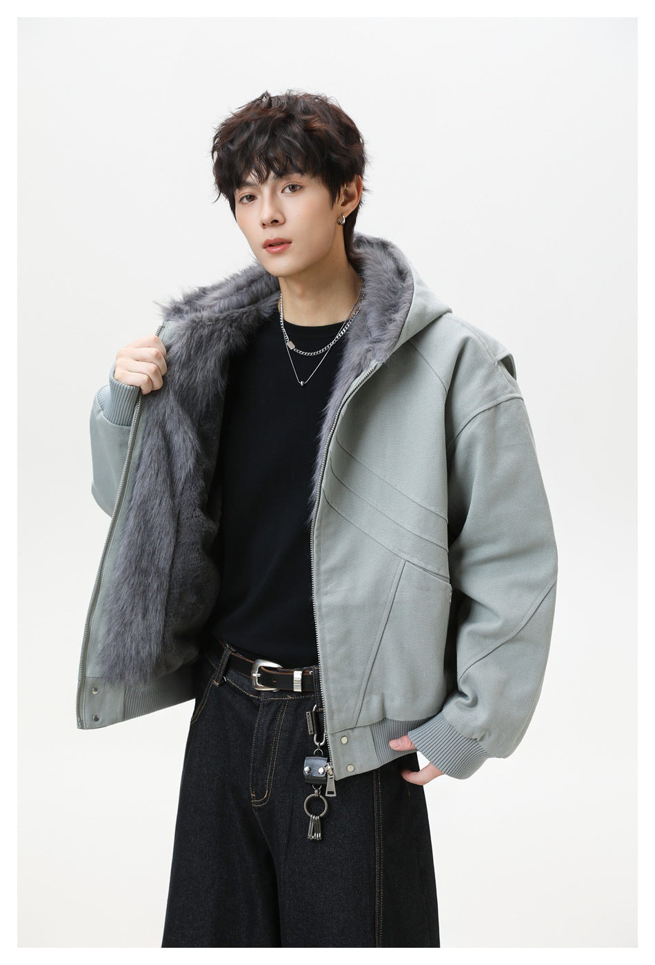 Model holding open a gray hooded jacket to show the dark gray fleece-like lining, with black top and dark jeans