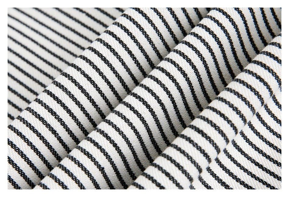 Close-up of folded cream fabric with narrow black stripes, showing its texture and drape.
