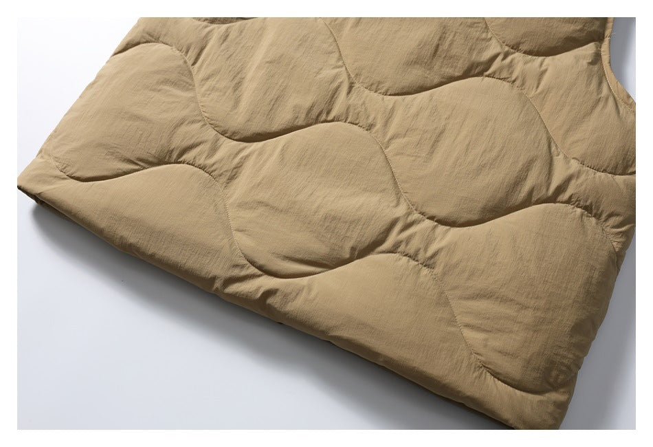 Close-up of tan padded jacket fabric with large curved quilted panels and stitched seams.