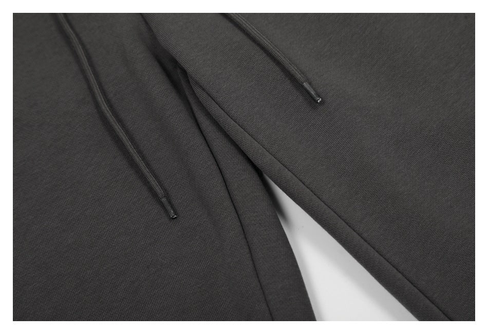 Close-up of charcoal pants with two dark drawstrings and overlapping fabric panels.