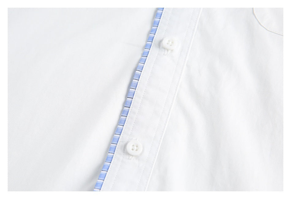 Close-up of two white buttons and blue-striped trim along the placket of a white shirt.