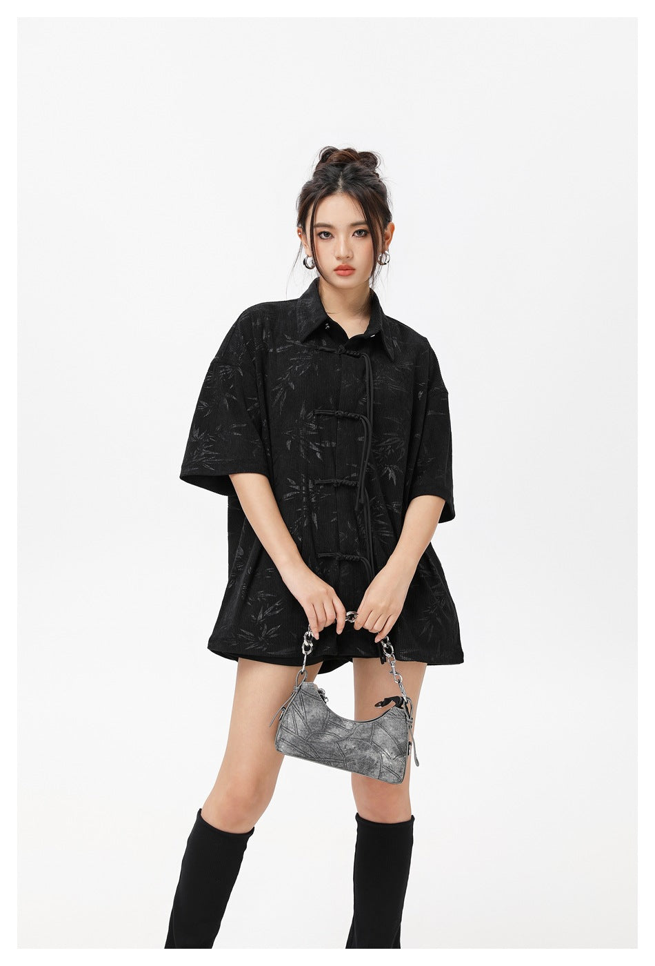 Model wearing an oversized black leaf-pattern shirt with a pointed collar and knotted front closures.
