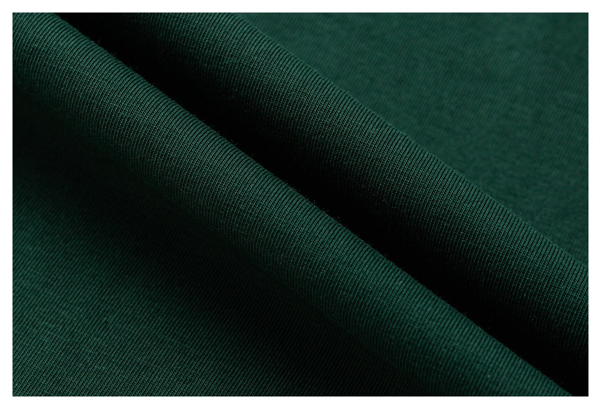 Macro view of dark green fabric arranged in folds, showing its fine surface texture.