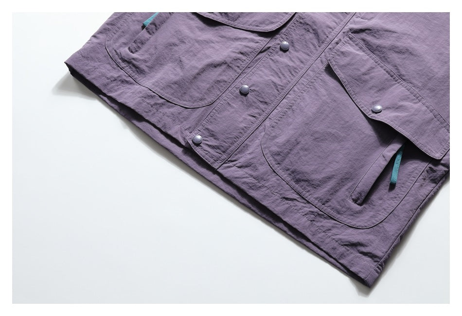 Close-up of the purple jacket front with snap buttons, flap pockets, and teal zipper pulls.