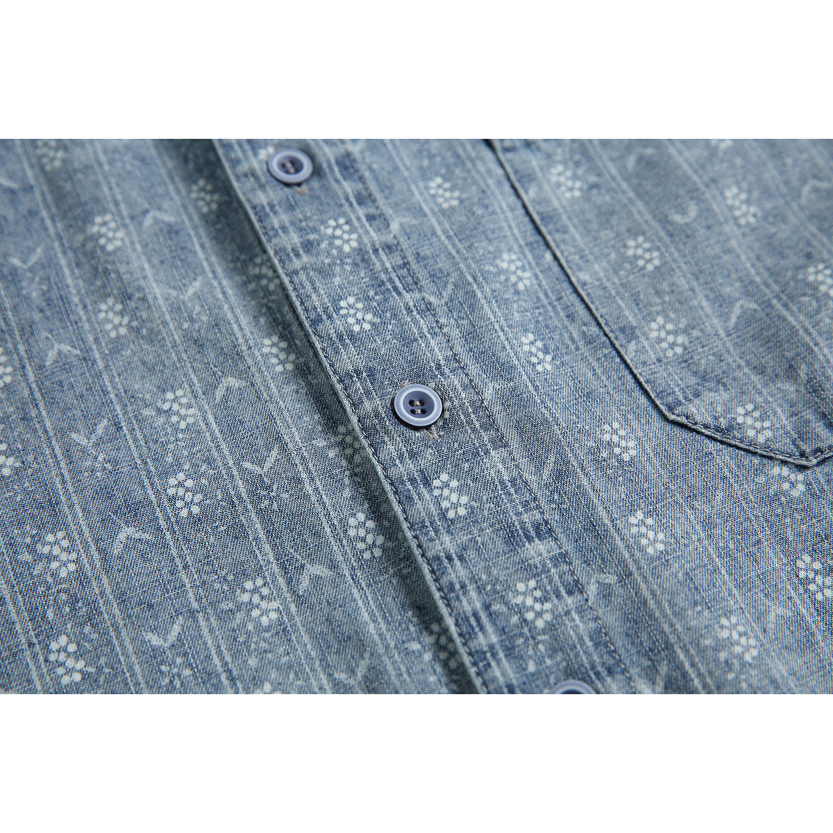 Close-up of blue-gray patterned shirt fabric, front buttons, and part of a chest pocket.