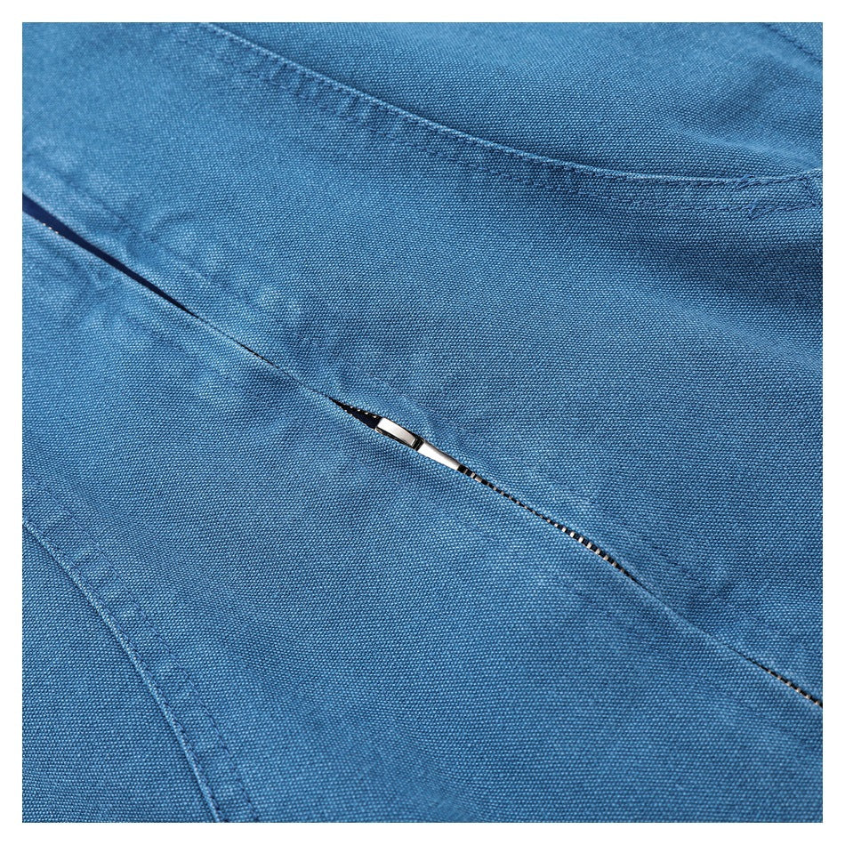 Close-up of blue jacket fabric, curved stitched seam, and a partially visible zipper.