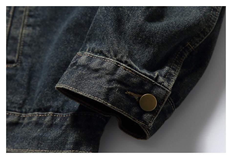 Close-up of a dark denim jacket cuff with contrast stitching and a brass-tone snap.