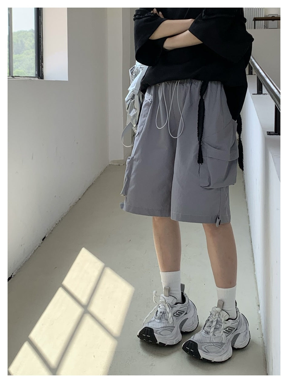 Side and rear view of a person wearing gray cargo shorts with a drawstring waist and large flap pockets.