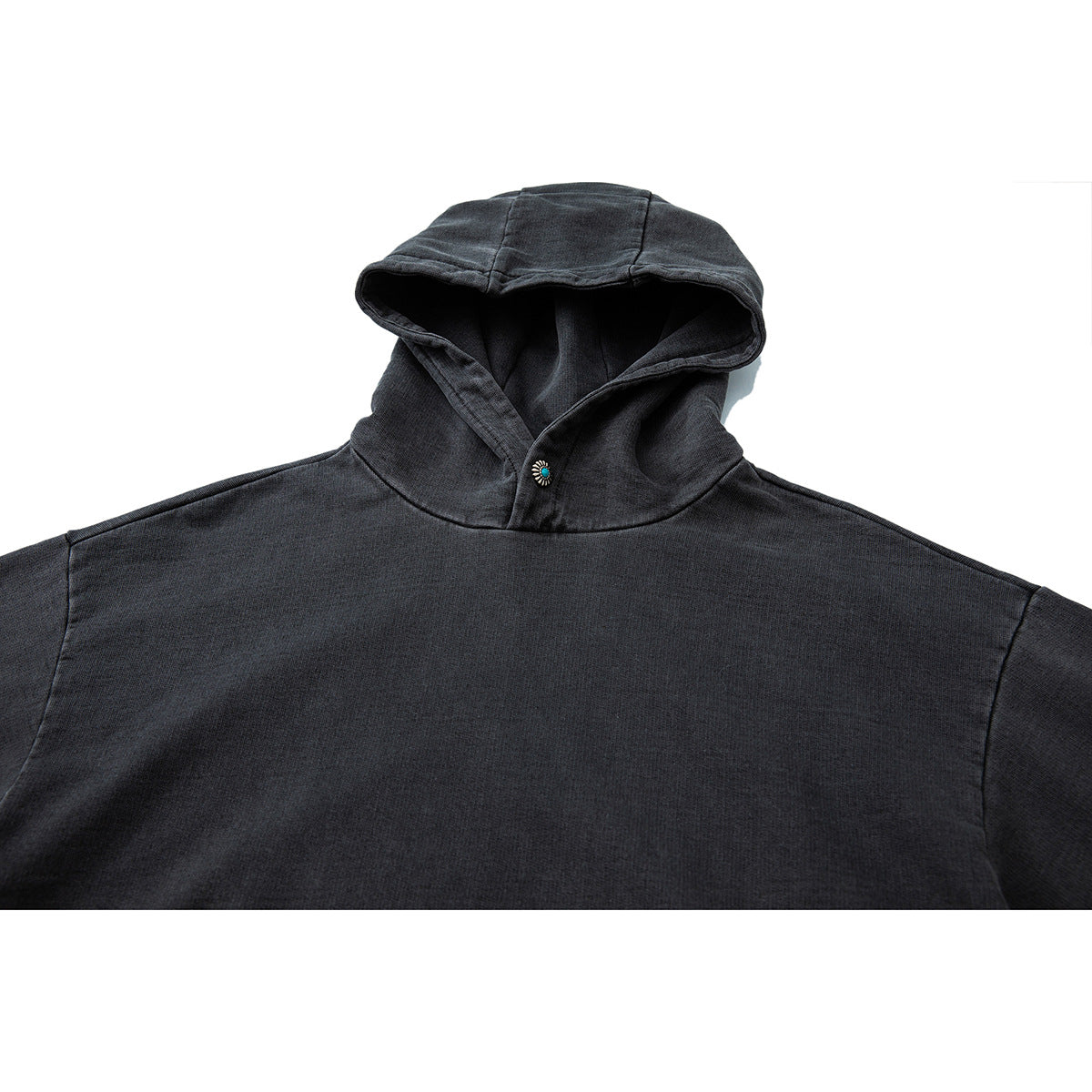 Close-up of a charcoal hooded pullover with a turquoise decorative button at the neckline.