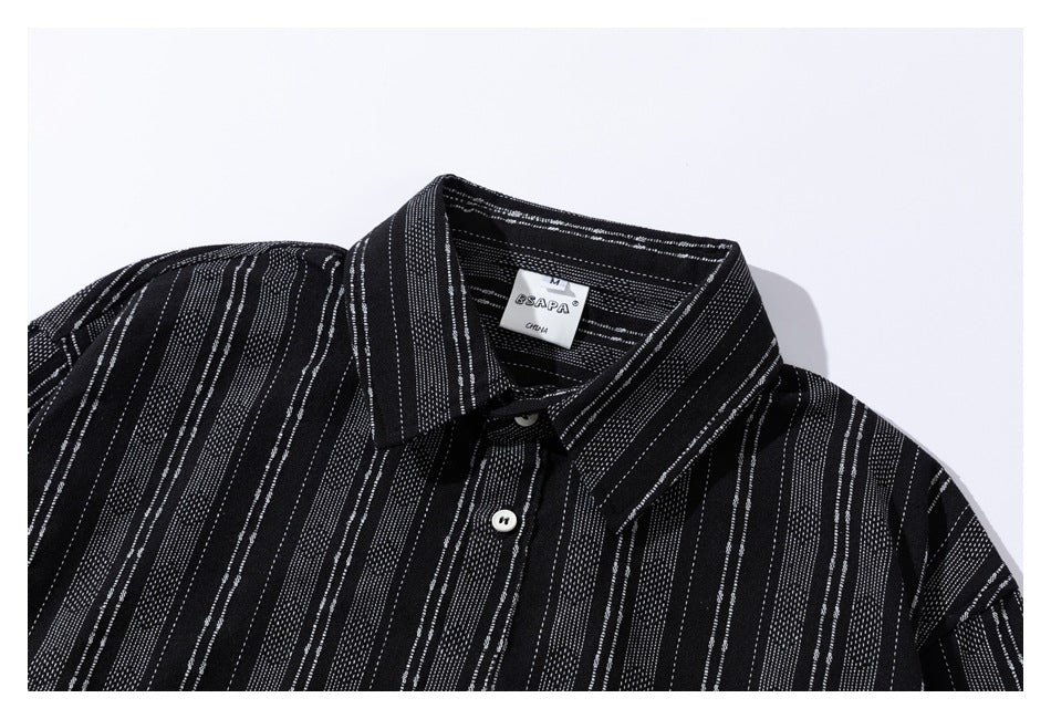 Close-up of a black striped shirt’s collar, top button, and sewn neck label.