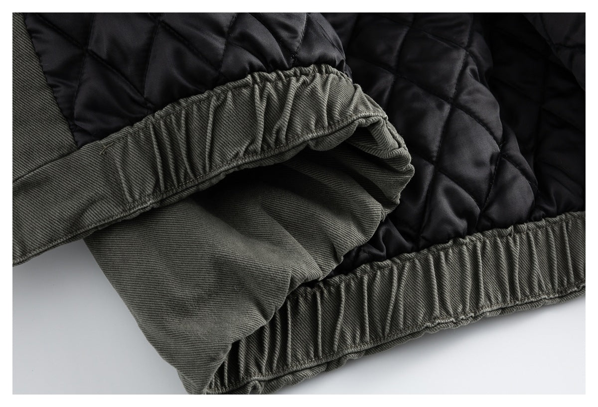 Close-up of an olive-gray jacket hem beside black quilted lining, showing gathered ribbed edging.
