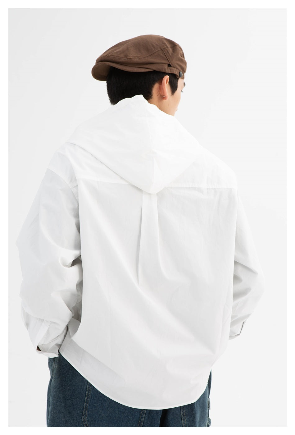 Back view of a model wearing a white hooded jacket with a center back seam and a curved hem.