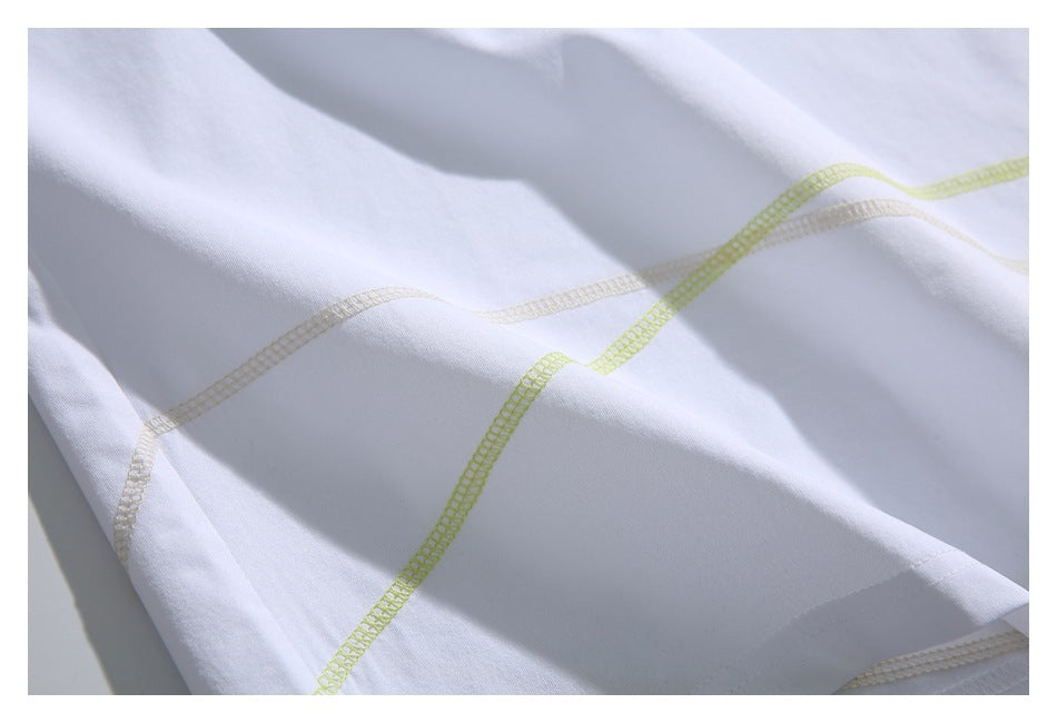 Macro view of curved pale yellow-green and beige overlock stitching on white fabric.
