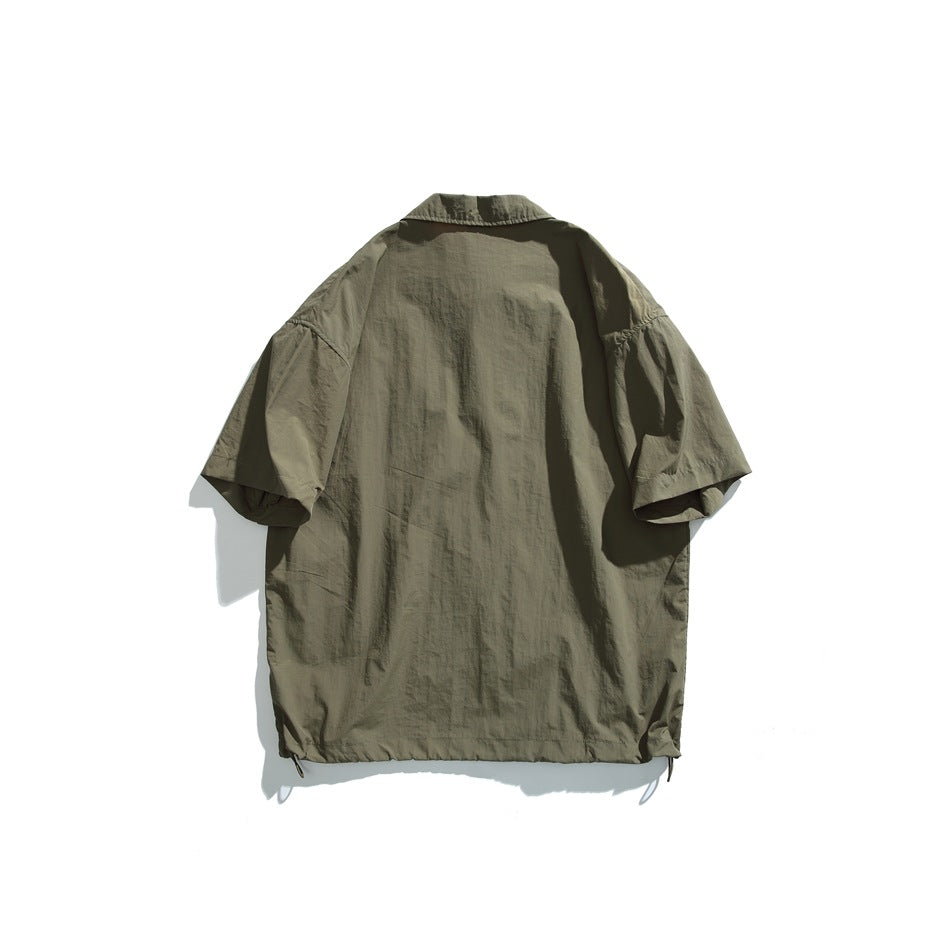 Back view of an olive green short-sleeve pullover shirt with a pointed collar and adjustable hem drawcords.