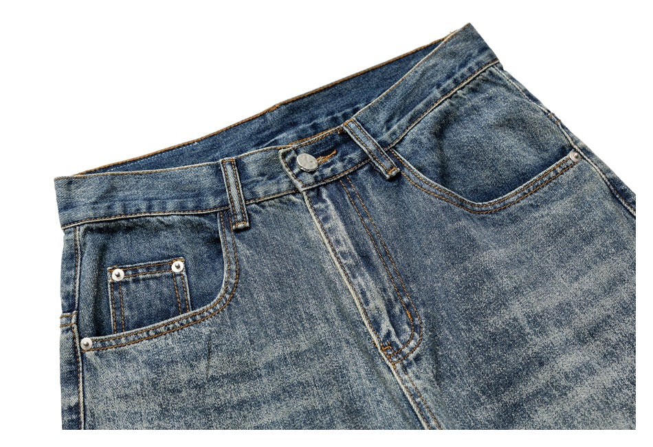 Cropped front view of blue faded jeans showing the waistband, button, fly and front pockets.