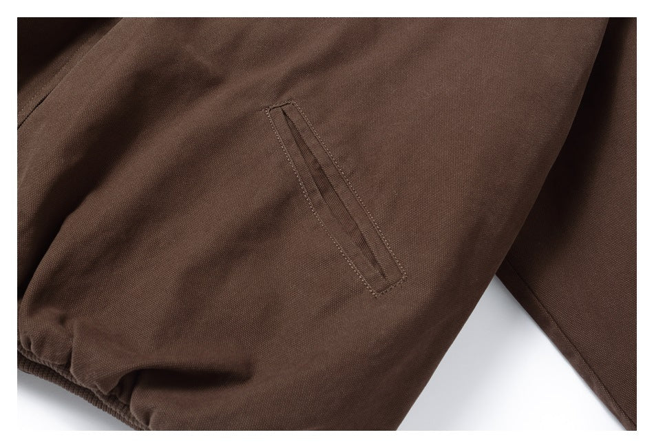 Close-up of a dark brown jacket's narrow welt pocket and gathered cuff.