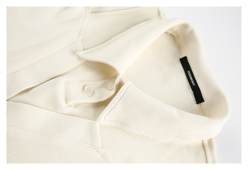 Close-up of an ivory top's pointed collar, two-button placket, stitching, and neck label.