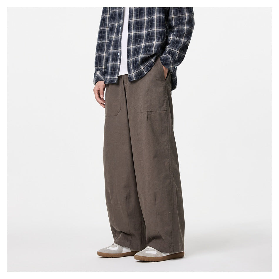 Side view of model wearing brown wide-leg pants with patch pockets, plaid shirt and gray sneakers