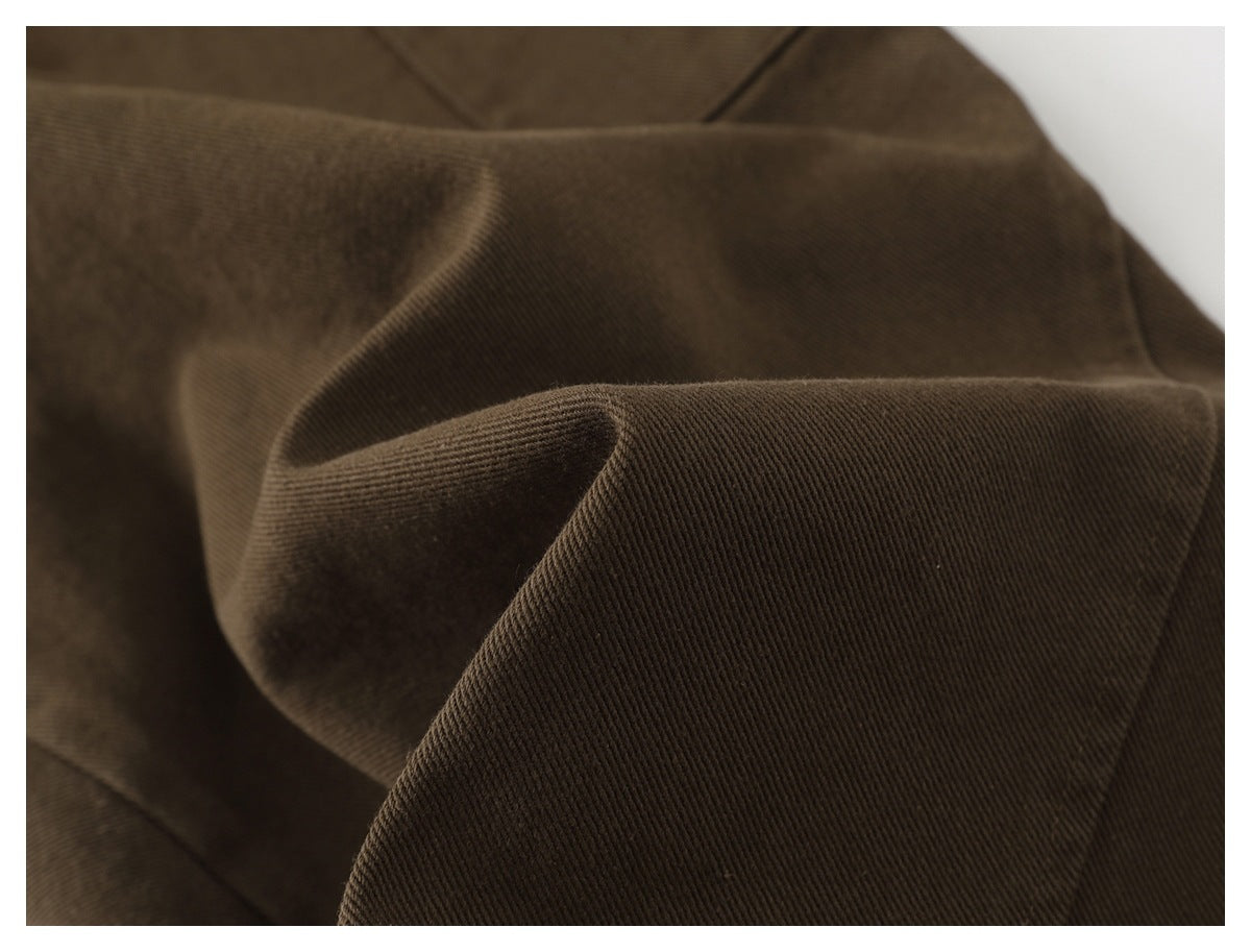 Extreme close-up of dark brown fabric showing a fine diagonal ribbed texture and soft folds.