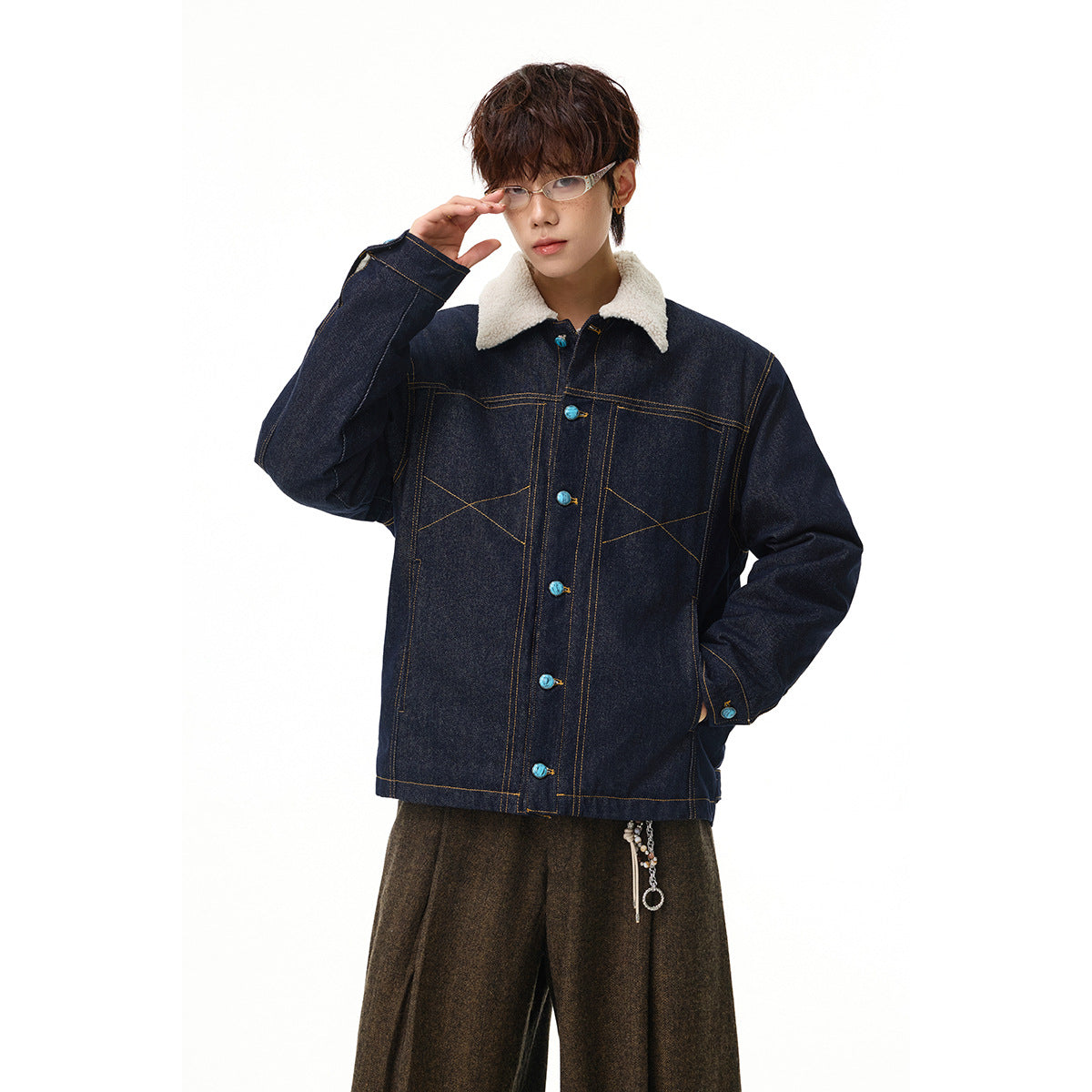 Model wearing a dark indigo denim jacket with a cream sherpa collar, contrast stitching, and turquoise buttons.