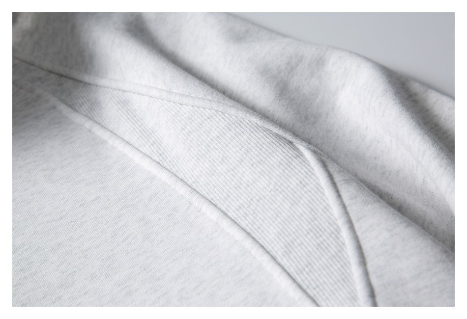 Close-up of a light gray hoodie seam and ribbed fabric panel.
