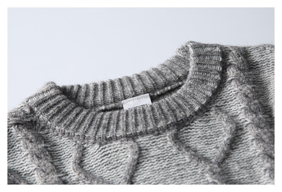 Close-up of a gray patterned knit sweater with a ribbed crew neckline and small white tag.