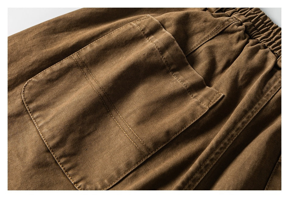 Close-up of a large stitched patch pocket on the brown trousers.
