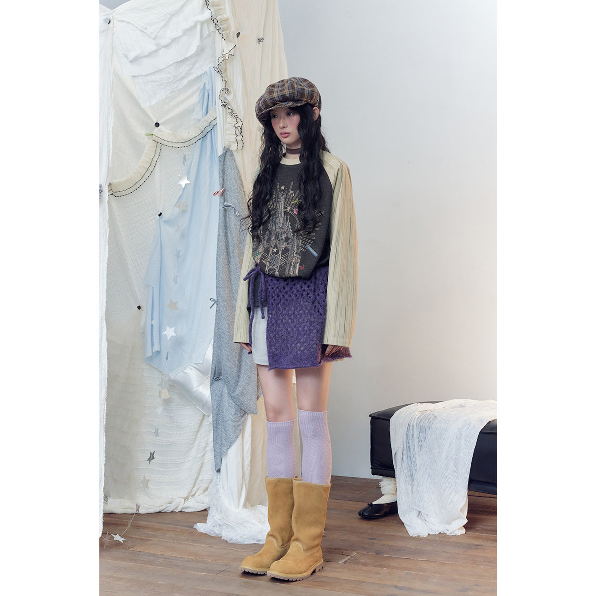 Full-length model wearing a charcoal graphic raglan top with cream striped sleeves and a purple knit wrap skirt.