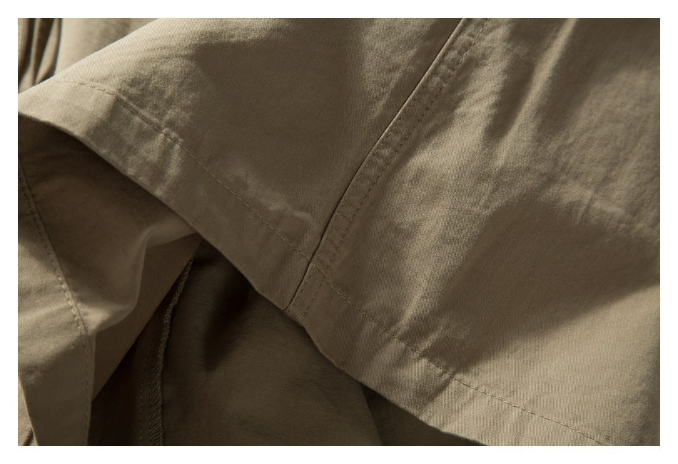 Close-up of beige shorts showing overlapping fabric panels and stitched seams.