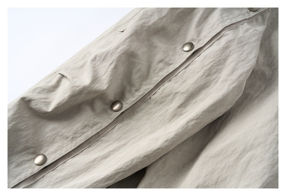 Close-up of the jacket’s light beige-gray front placket with metal snap buttons.