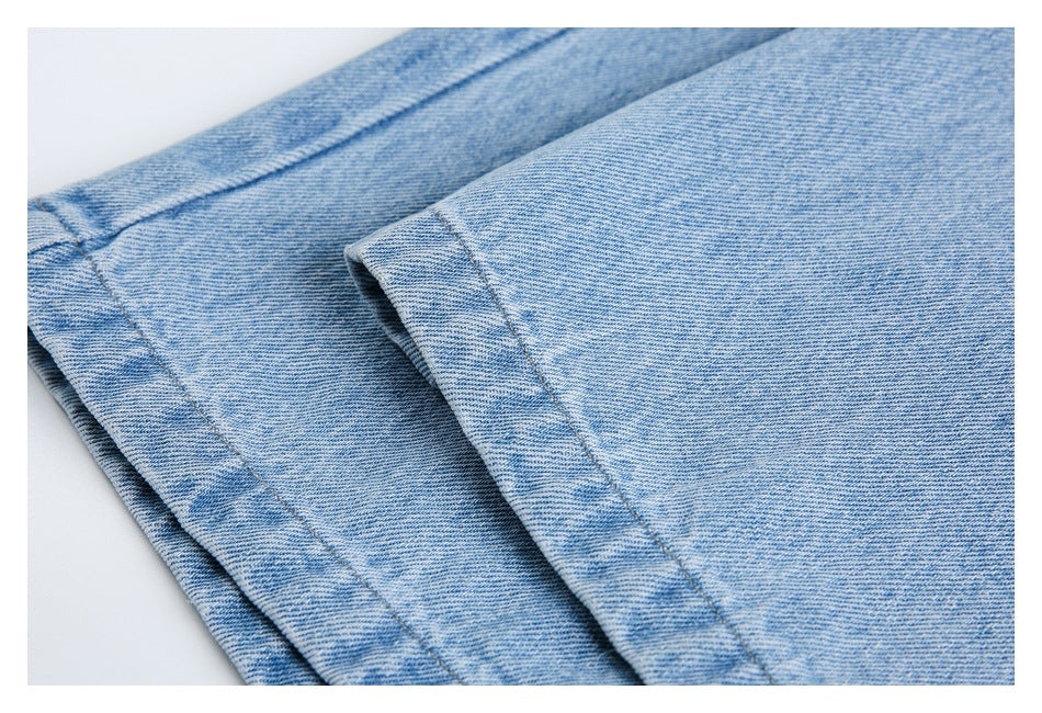Close-up of overlapping stitched denim panels on light-wash blue jeans.