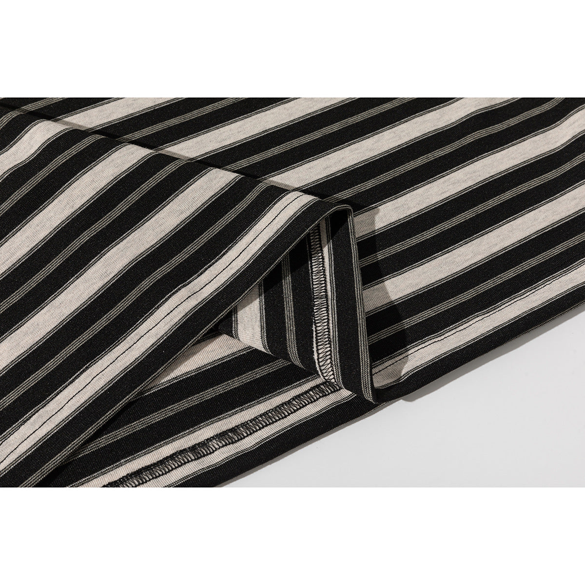 Close-up of the black and beige striped T-shirt fabric and overlocked hem seam.