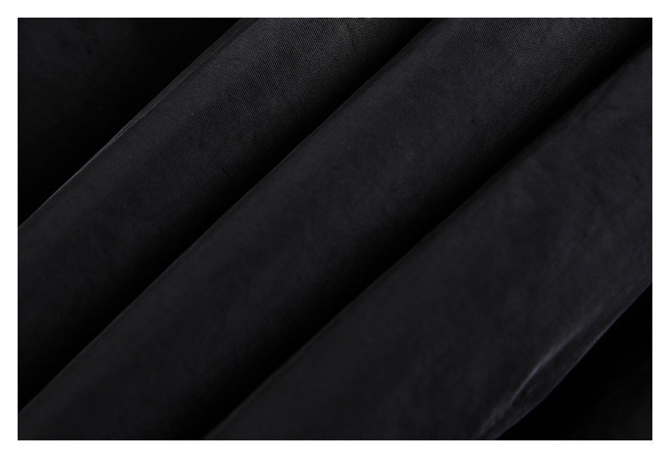 Close-up of black garment fabric arranged in soft folds, showing its surface texture.