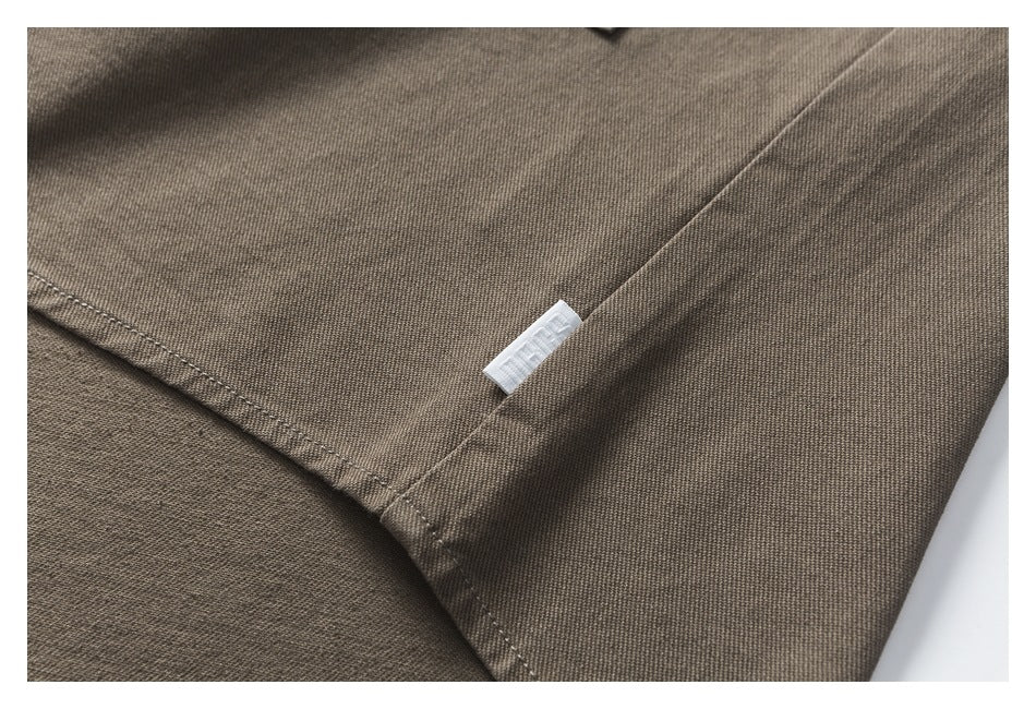 Close-up of a seam and small white fabric label on brown-gray garment fabric.