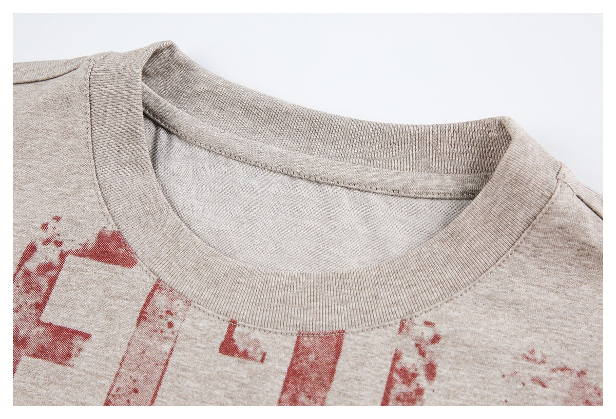 Close-up of the ribbed crew neckline and shoulder seams on a beige heather T-shirt.