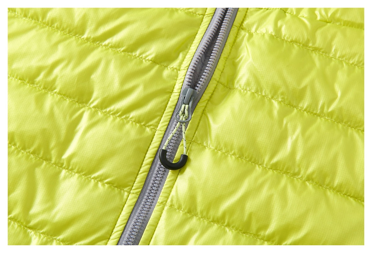 Close-up of the chartreuse vest's gray front zipper, cord pull, and quilted panels.