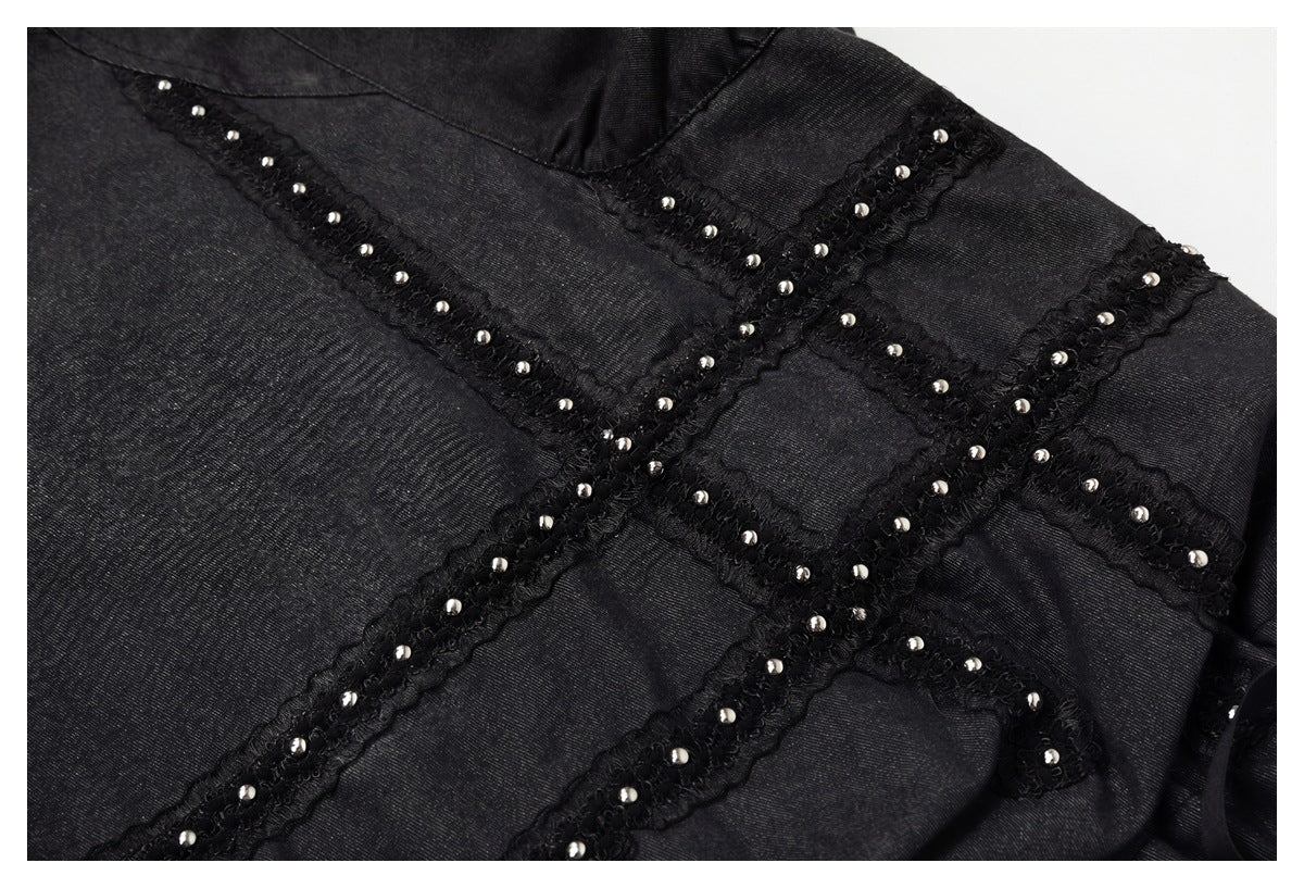 Close-up of black garment panels with intersecting lace-like trim decorated with silver studs.